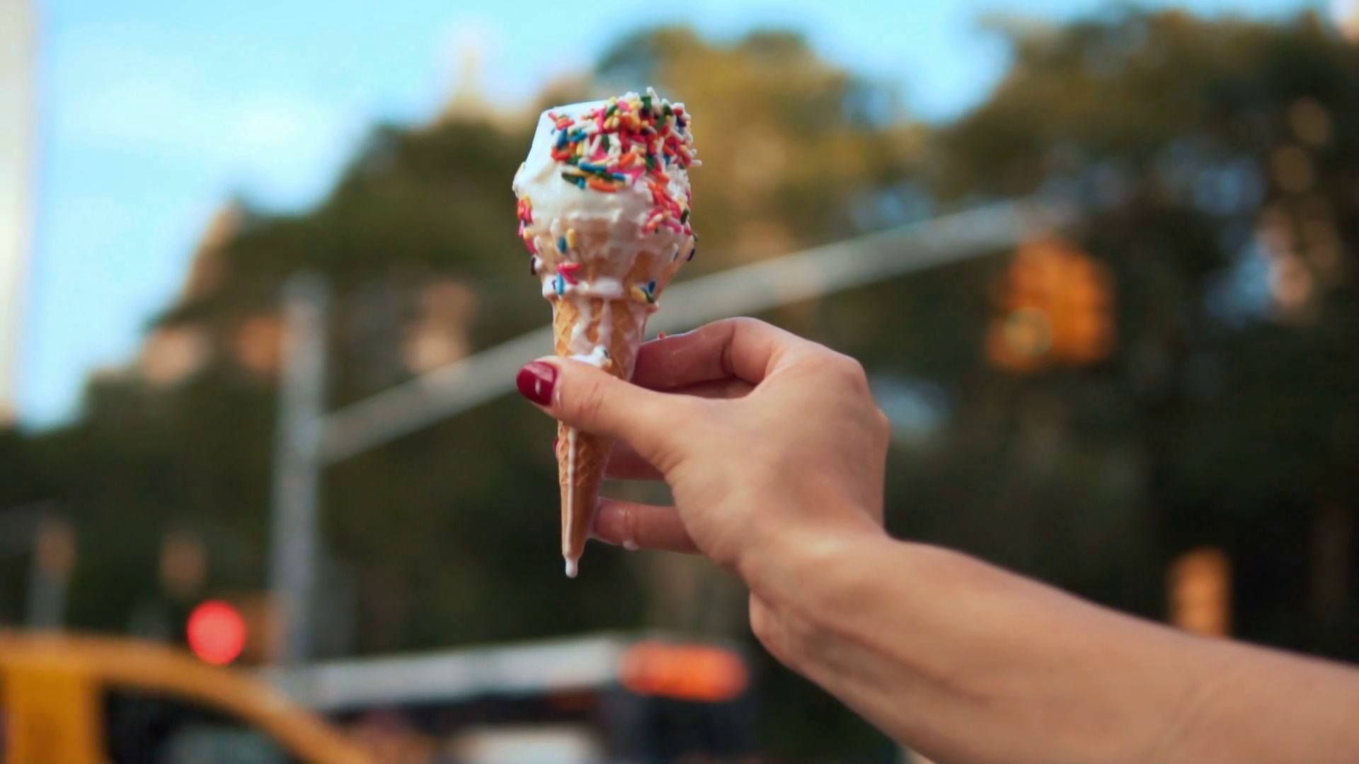 Close-up view of melting ice cream with topping held by young woman