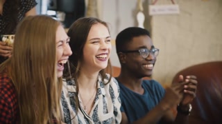 Happy friends watch sports on TV, celebrate victory. Diverse supporters fans shout together. Emotion. Slow motion.