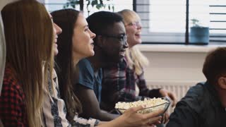 Happy mixed race millennials watch TV together. Slow motion close up. Multi ethnic fans support favourite team. Emotion.