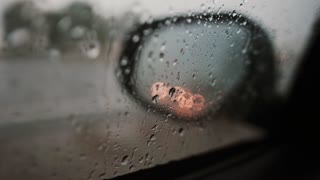 Raindrops and reflection of lights on a side mirror of a car.