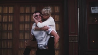 Slow motion joyful young woman sitting on her partner's back, laughing and embracing during a lovely date.