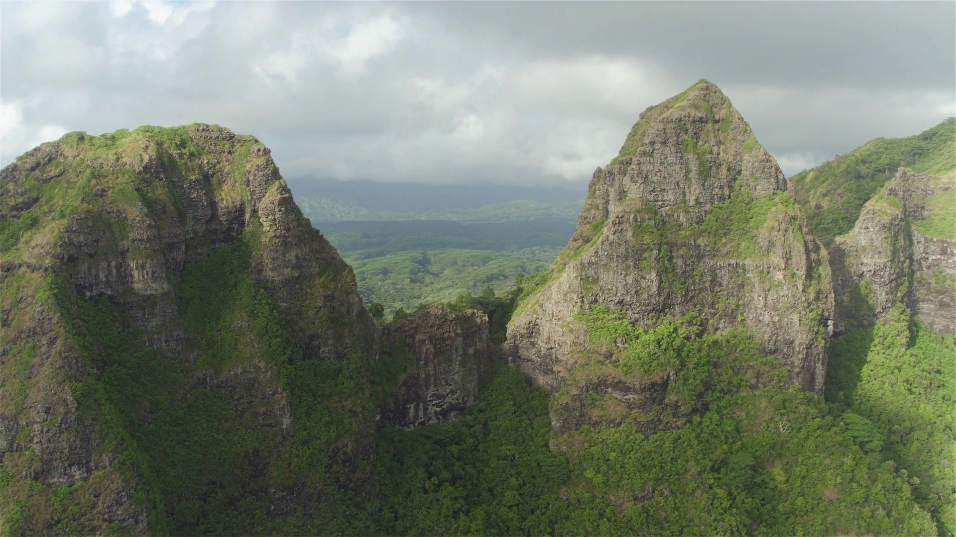 AERIAL: Flying between majestic mountain tops above lush rainforest