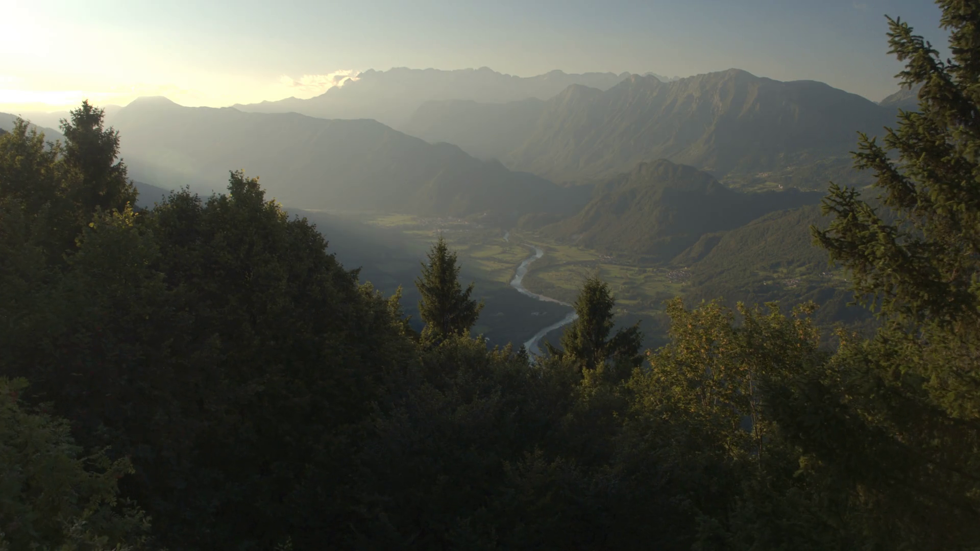 AERIAL: Meandering river winding through mountain valley in misty
