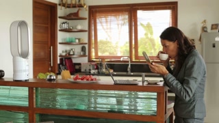 Businesswoman correcting makeup in the kitchen and drinking coffee