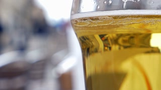 Close-up shot of a glass with light beer. Refreshing alcoholic beverage. City reflecting in the glass. Munich Beer Festival