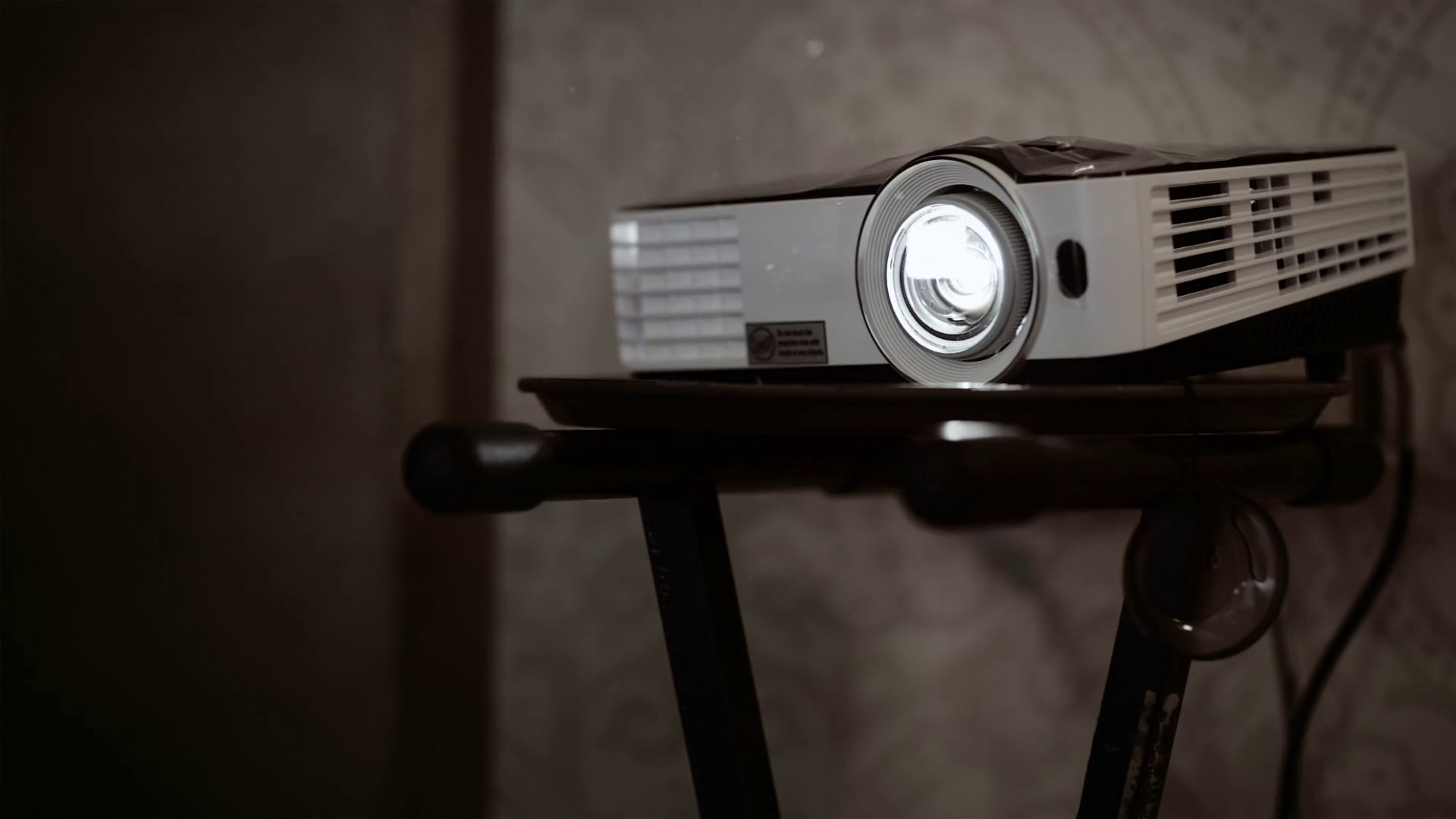 Digital multimedia projector standing on the rack in work. Bright light