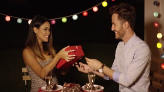 Happy woman receiving a Valentine's gift from a kind man during a lovely meal