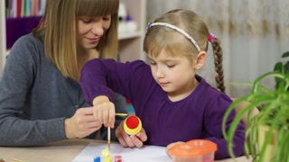 Mother and child decorate an Easter egg. Drawing lessons in the family