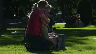 Mother And Son Put Flowers On Grave