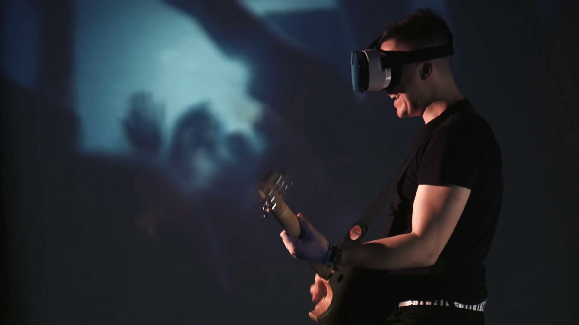 Smiling young man playing guitar while wearing oculus rift goggles