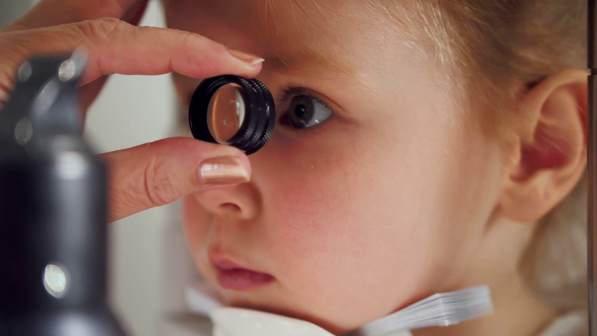 Child's ophthalmology doctor optometrist checks eyesight for little