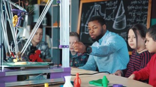 Excited school kids and teacher examining technology of three dimensional printing in laboratory. Static 4K shot on Red cinema camera.