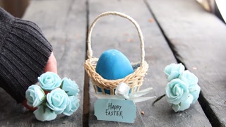 Happy easter. Egg on rustic table and a basket with a blue label