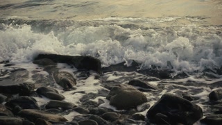 Slow motion a storm wave rolls over a stony shore