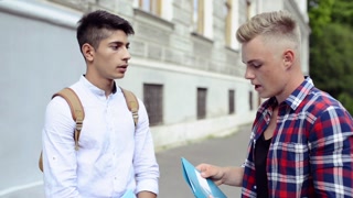 Two teenage students in front of university talking.
