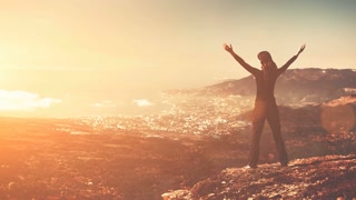 Silhouette of woman on mountain peak. Resort town and Black Sea in valley. Soft sunset light with sun beams. Vintage yellow toning. Slow motion 4K.