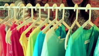 Women talking and looking on the clothes on the hangers