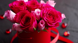 Pink roses bouquet packed in red box and placed on black stone background with copy space. Valentines day or Romantic concept.