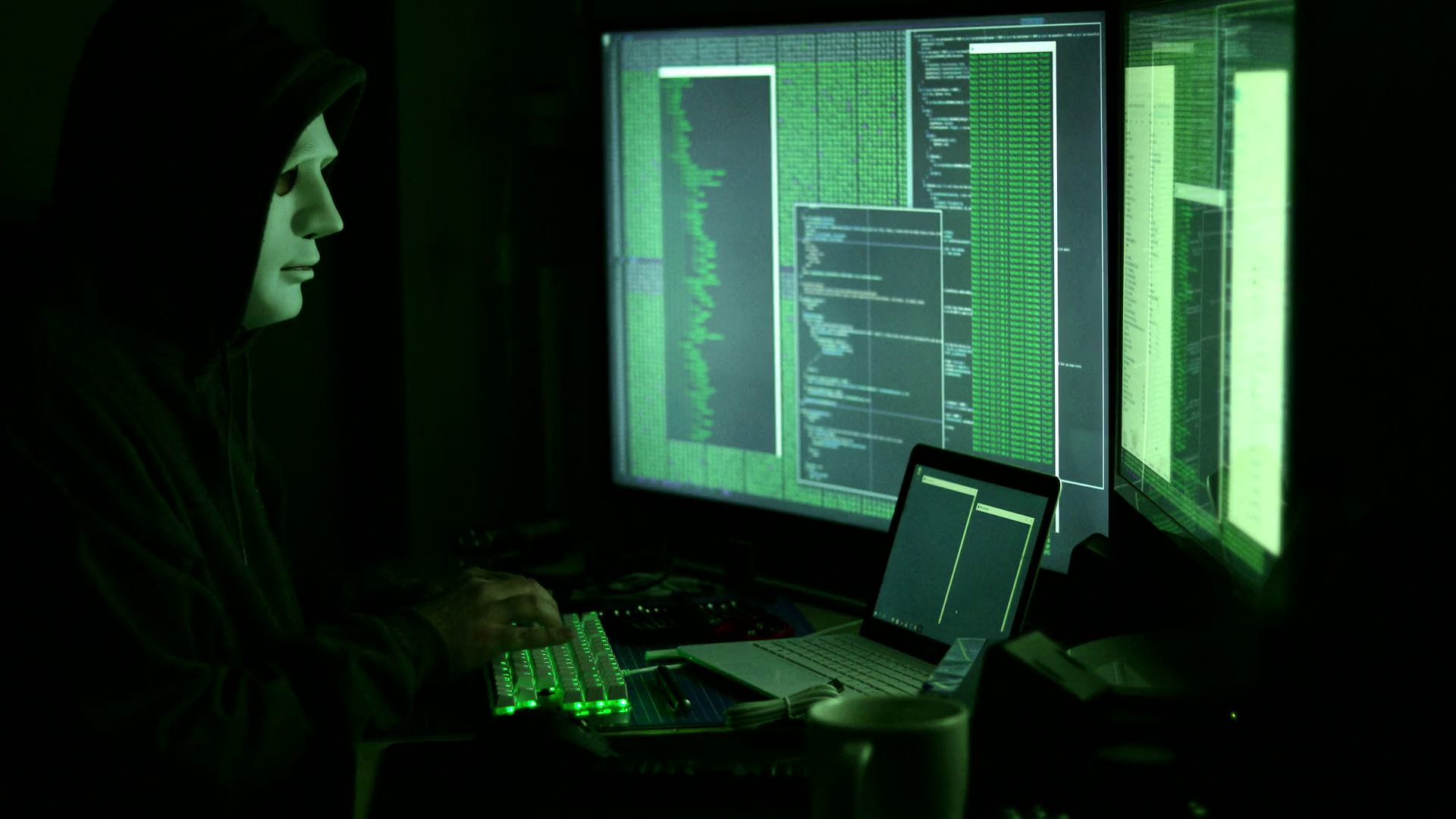 Side view of man in mask and hood hacking worldwide network using