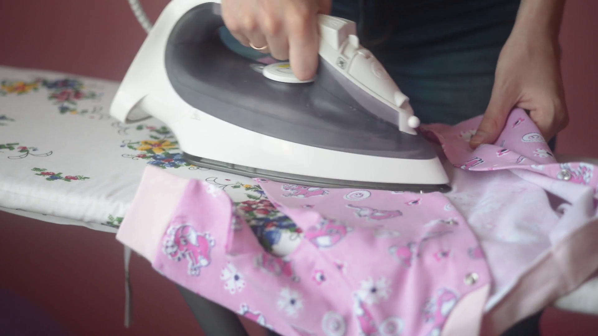 young woman ironing baby clothes on an ironing board at home Stock