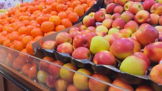 Grocery store with fresh fruits, apples and mandarins neatly displayed on shelves. Close up