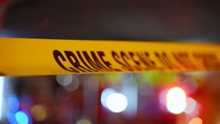 A bright yellow Crime Scene tape across an urban environment, marking a restricted area for investigation. Police or rescue team flashing