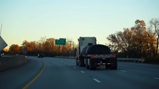 Semi-truck with open deck trailer is traveling on a highway at golden autumn sunset. long-haul freight transportation on an American