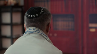 POV of Jewish Men from the back, covering a traditional Jewish Tallit blue and gold stripes and tassels. Praying