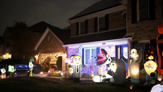 House decorated with colorful inflatable Halloween characters and glowing lights. Festive front yard display, neighborhood Halloween