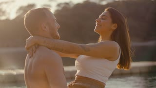 Man holds his beloved in his arms. Couple kissing and hugging in rays of setting sun
