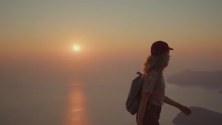 Portrait of girl traveler walking on top of mountain with backpack at sunset