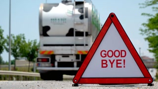 Goodbye sign on the road with a car driving away in the background