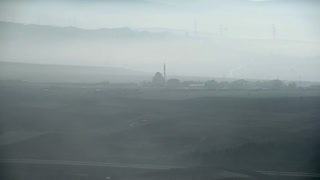 8K Timelapse fog reveals mosque silhouette across Anatolian plain in Turkey at dawn. Haze blankets a minaret outline, spiritual skyline drifting through cloud sea over highlands.