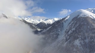 Aerial view of sunny sky above clouds in snowy mountains and valleys