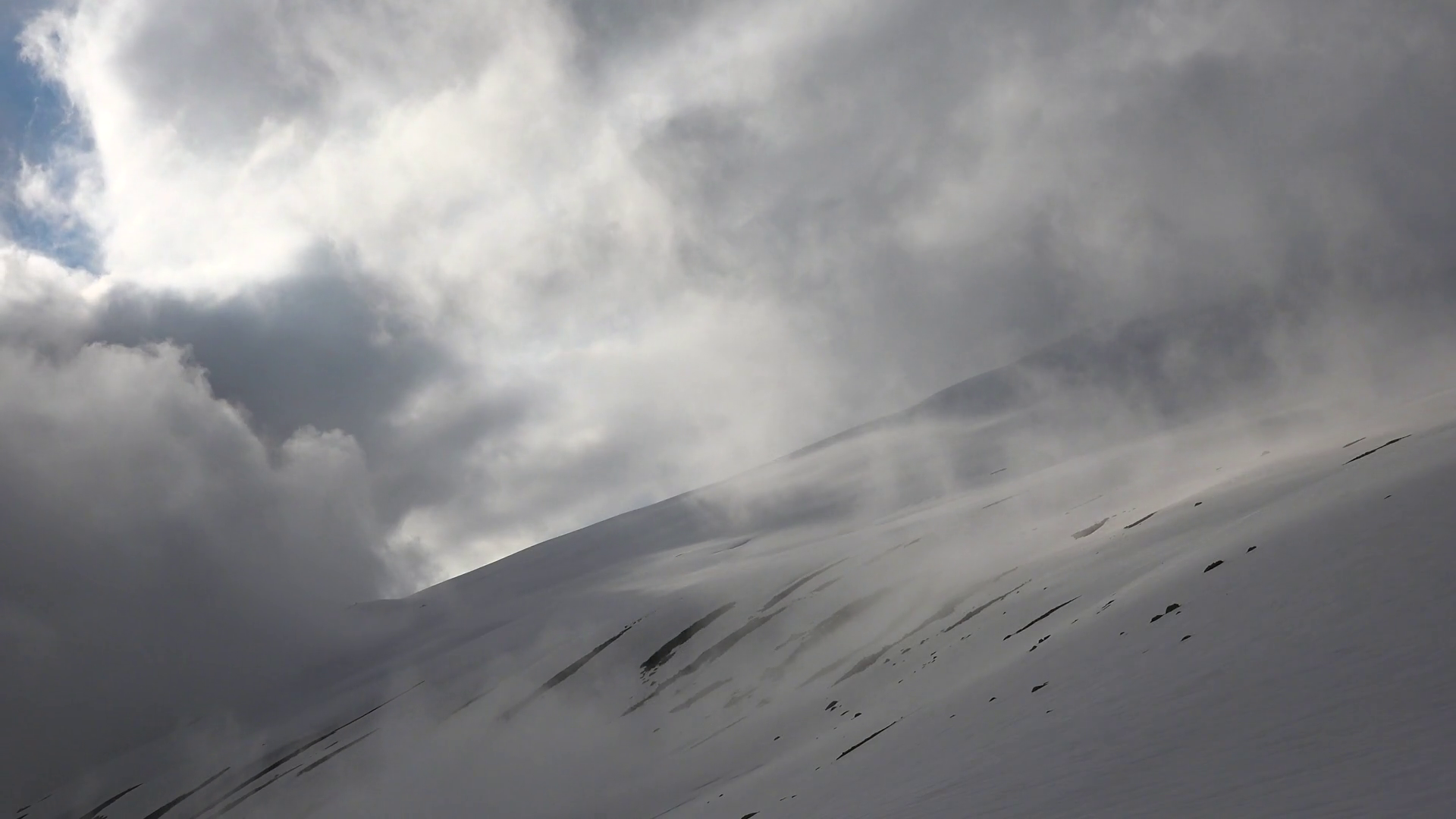 storm-clouds-on-high-altitude-treeless-and-smooth-snowy-mountain-slope