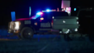 Defocused Police Vehicle with Flashing Emergency Lights at Night Scene.