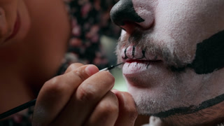 Makeup Artist Applying Day of the Dead Face Paint with Brush Close Up.