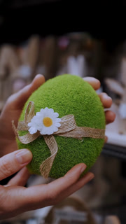Easter fair. close-up. female hands holding a figurine of a funny green Easter egg. traditional european easter decor and decorations. Easter shopping, display in a store.