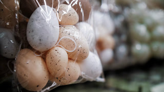 Colorful Easter egg figurines arranged in rows on a store display. Traditional European decor and festive merchandising.