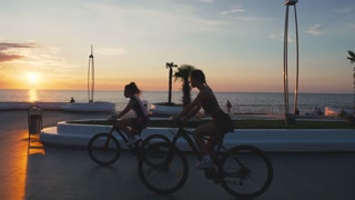 Diverse Friends riding bikes at embankment of city in the morning. Cycling sports, healthy lifestyle