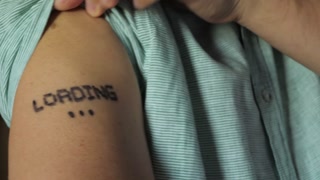 Unrecognizable man show LOADING text written on skin on forearm of human hand after vaccine injection. Paranoid thinking: fake news spread