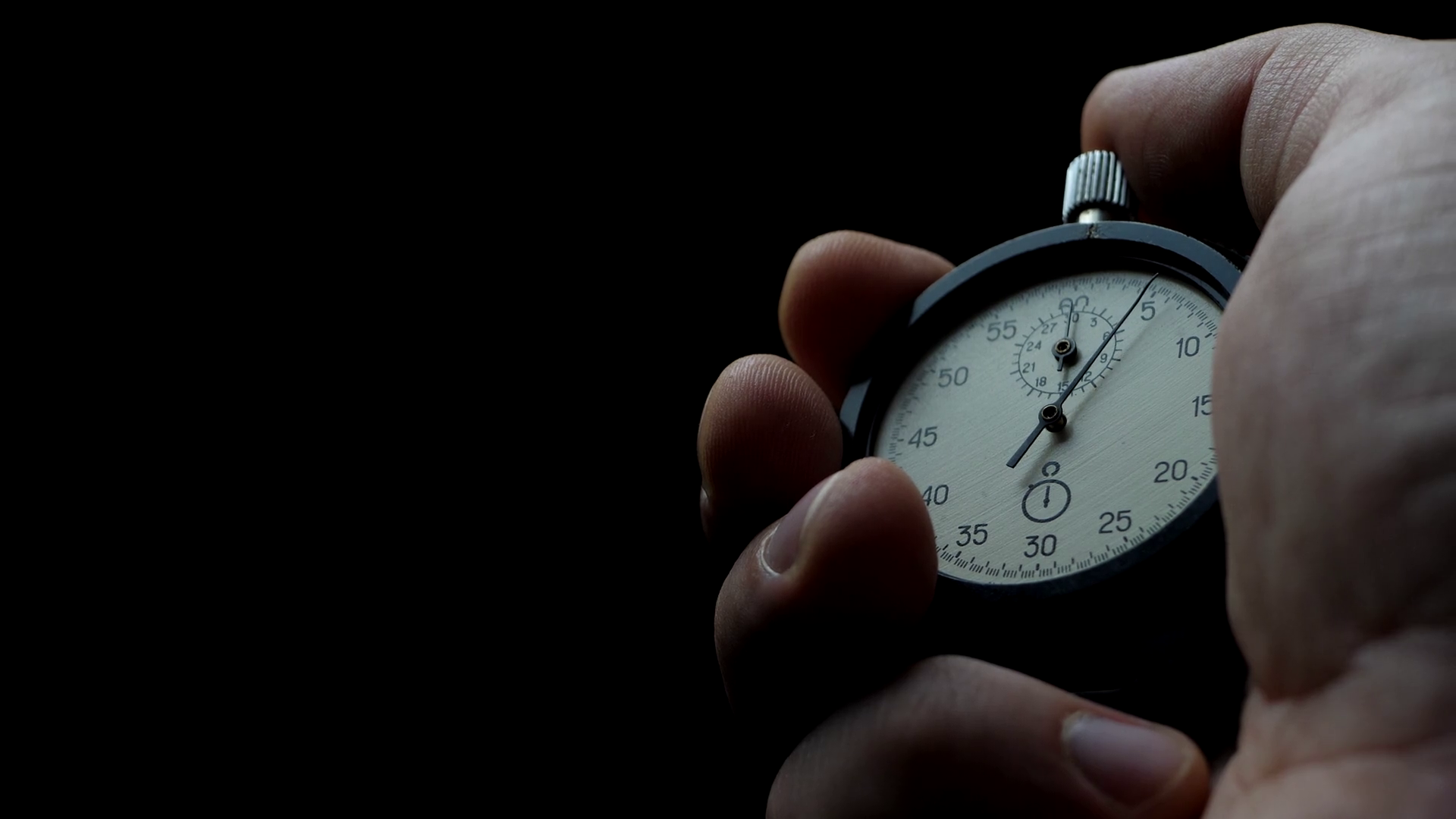 Analogue stopwatch in hand on the black background. Time start with old