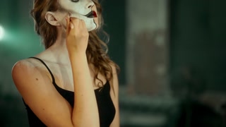 Professional actress drawing art makeup on her face, split personality, cosplay. Portrait of beautiful woman applying cosmetics on face by