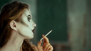 Attractive lady with cigarette posing and showing her fantasy makeup, closeup. Individuality and personality of modern independent woman