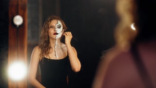 Portrait of professional actress applying makeup of comics character on face. Attractive lady preparing to theatrical performance or movie