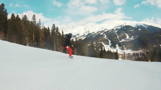 Woman Snowboarding Fast on Ski Slope Mountain. Snowboarder having fun snowboarding backcountry on a sunny winter day in snowy mountains.