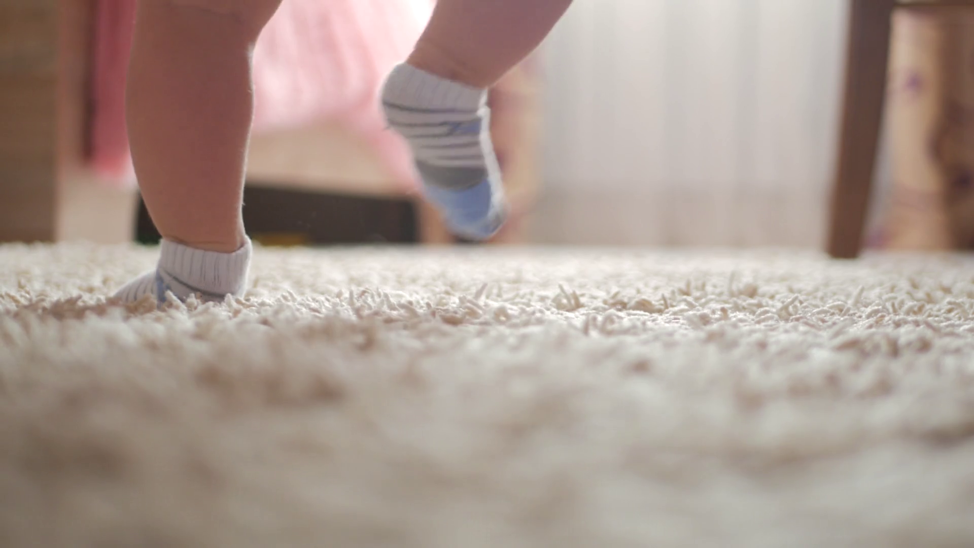 Closeup legs of little child walking by herself on the carpet in the