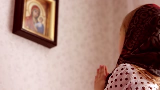 Young girl in a headscarf, praying at home in front of an icon. Concept, Russian Orthodox, Christianity.
