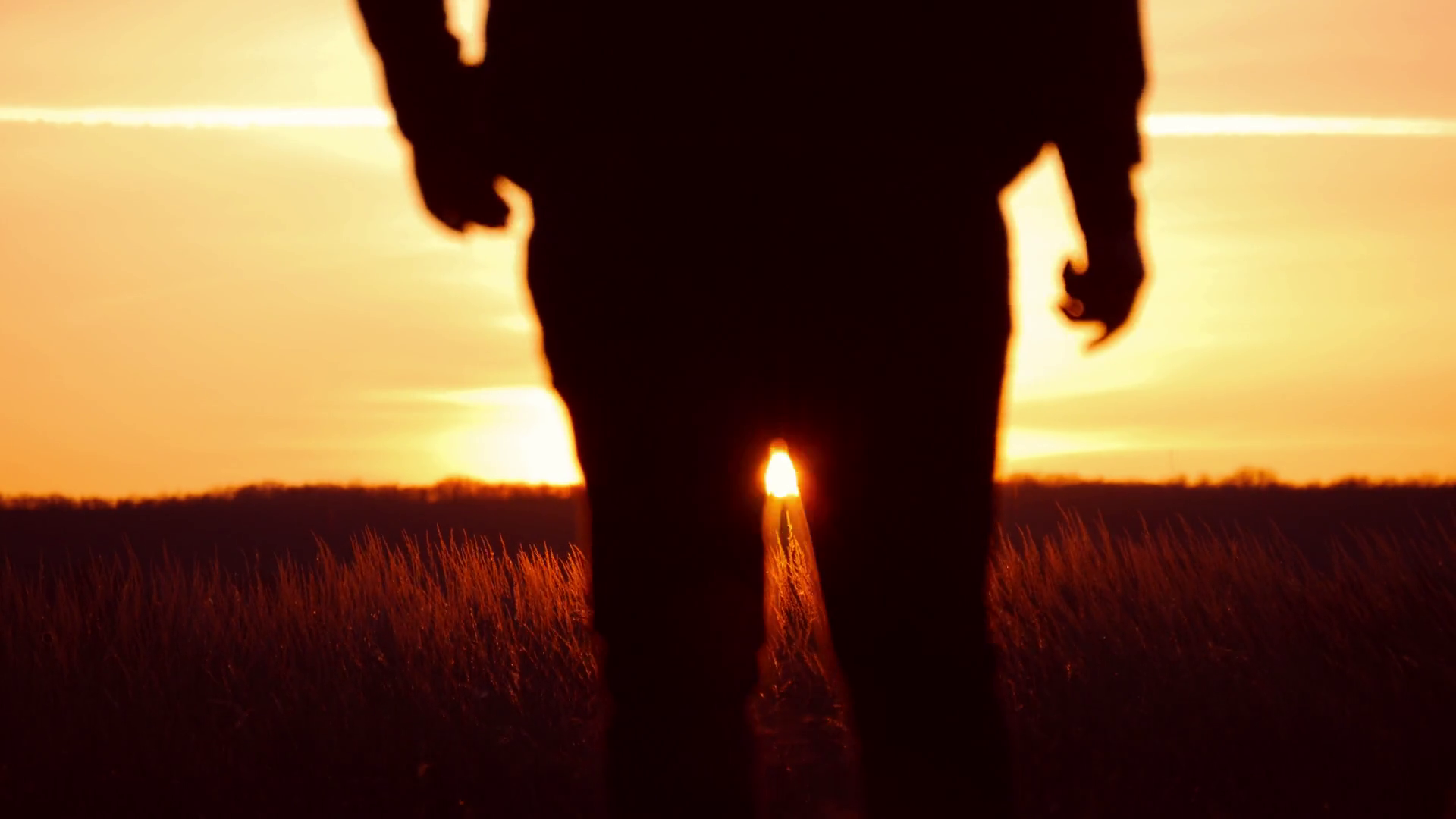 Silhouette of a man with hands raised in the sunset. Man with his arms