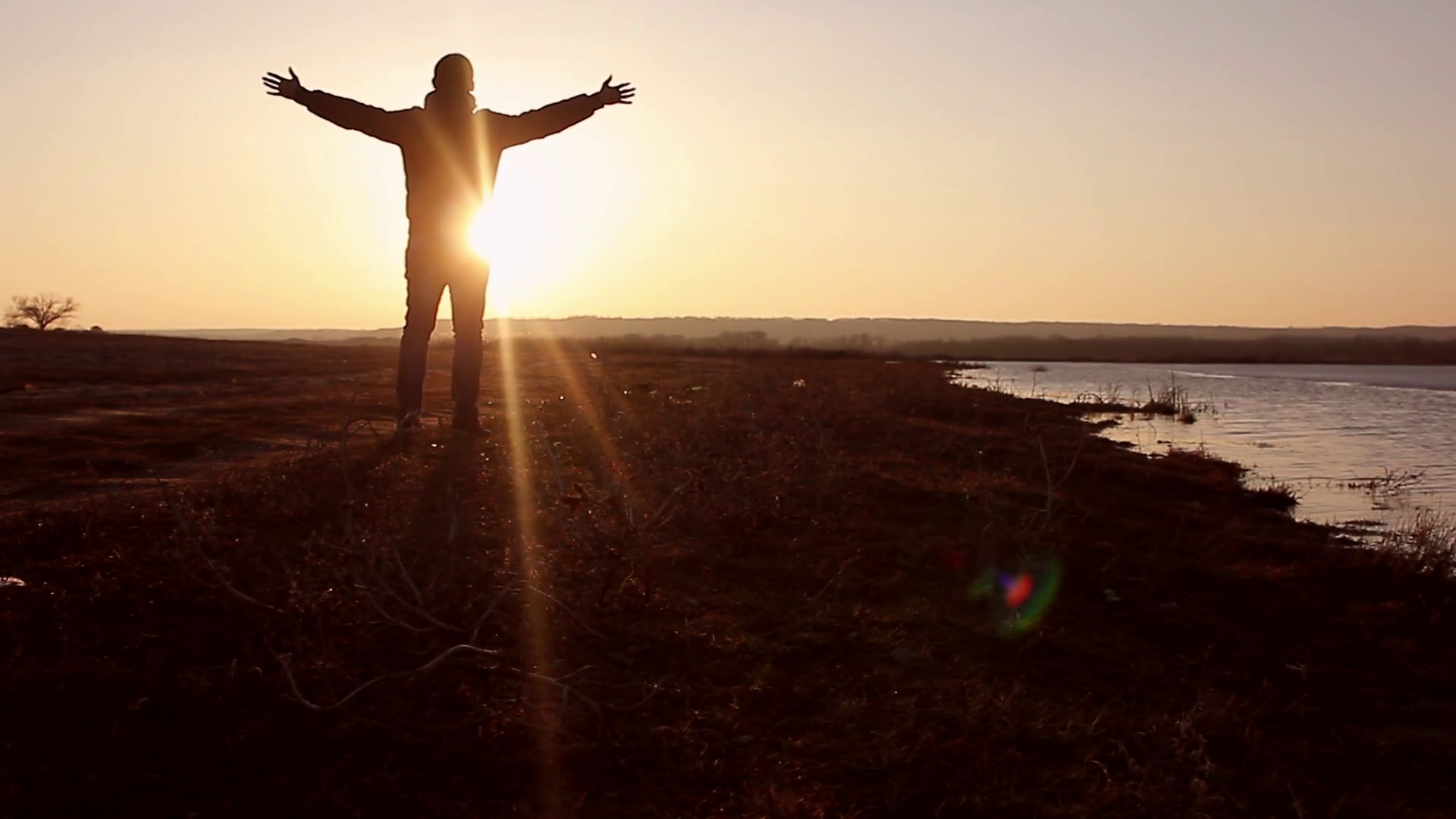Silhouette of a man with hands raised in the sunset. Man with his arms